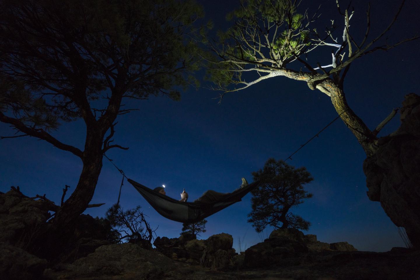 A person in a hammock outside at night