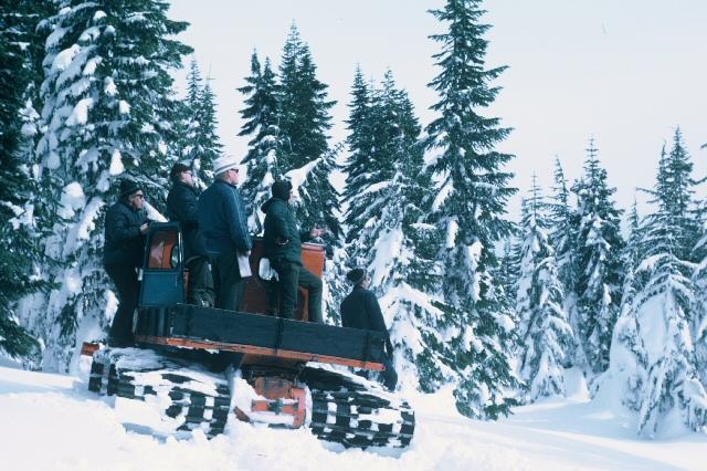 An old photo of people standing on a snowcat