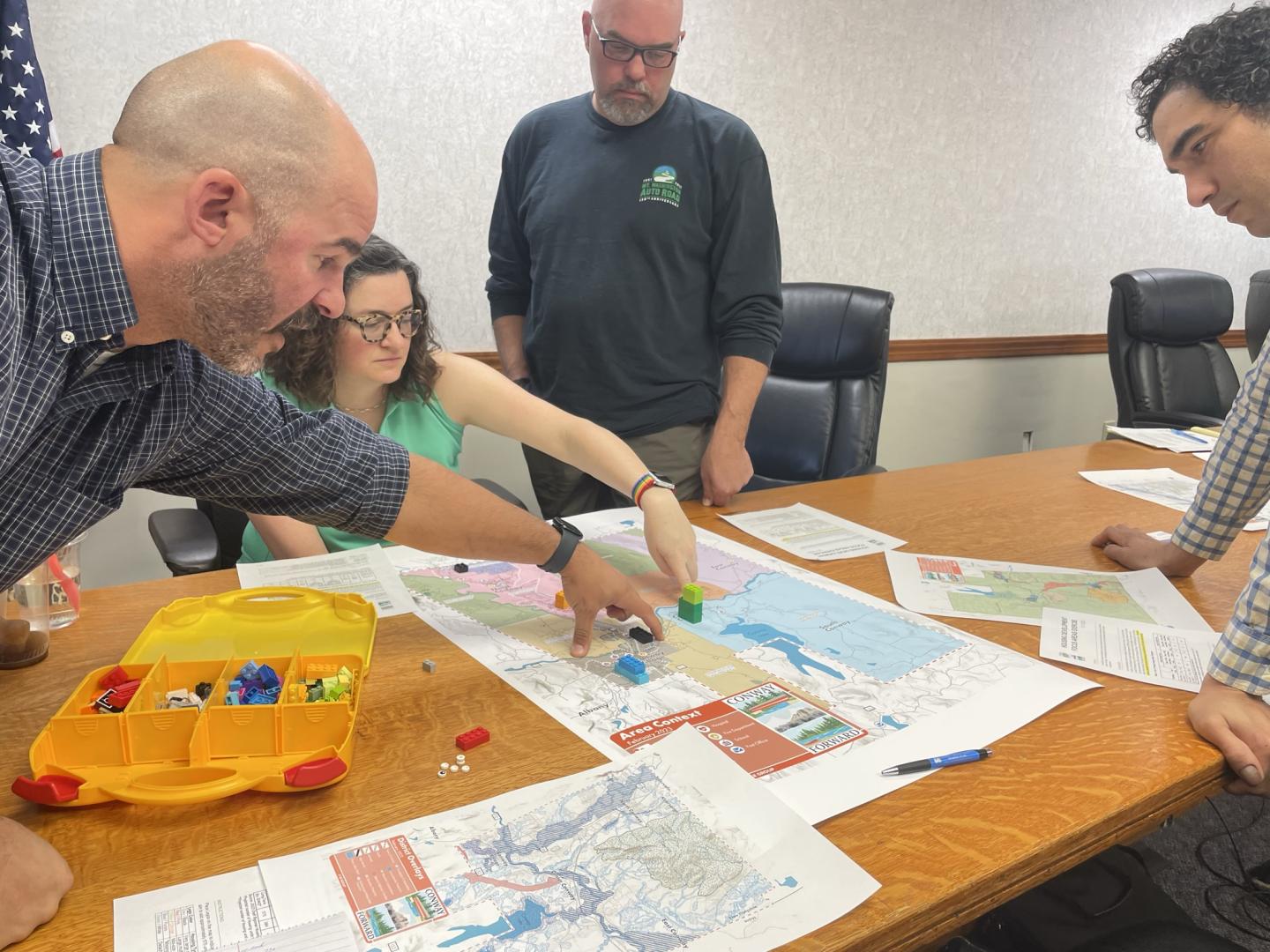People standing around a conference room table pointing at land use maps