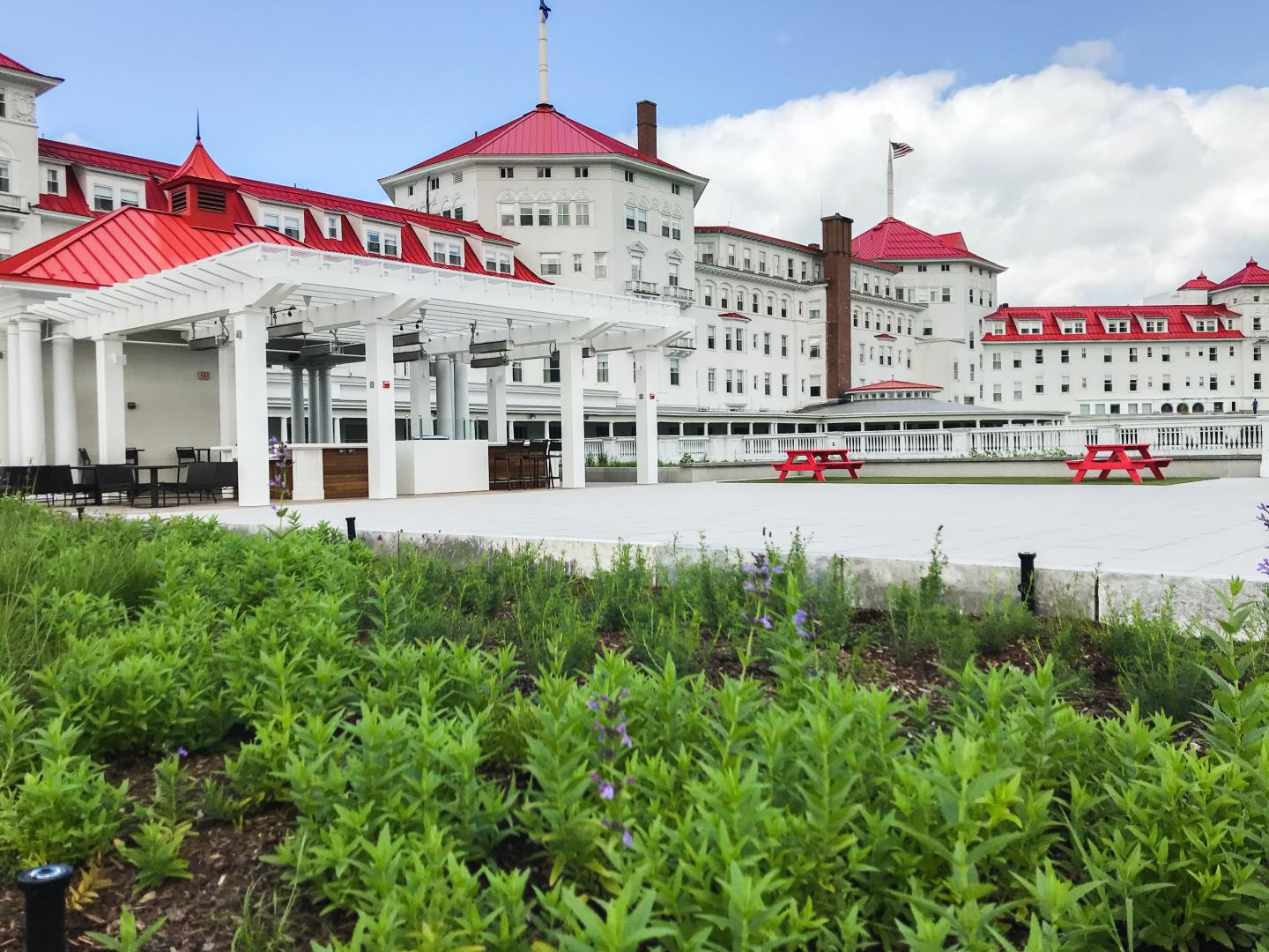 A view of Omni Mt. Washington hotel on a sunny day. White walls, red roof, and landscaping in front.