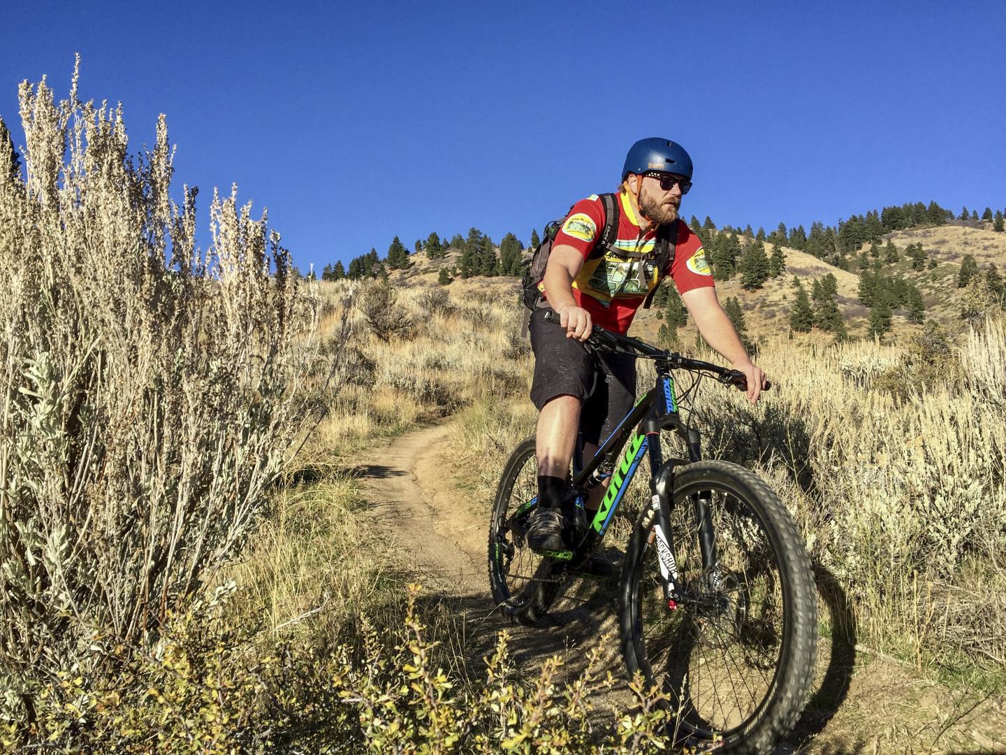 Mountain biker on a trail, clear blue sky overhead.