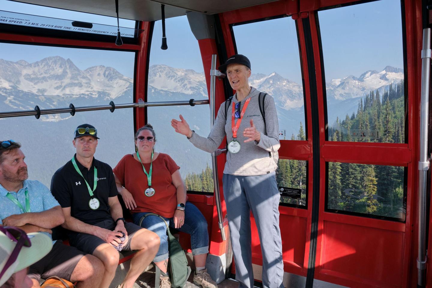 A group of people in a red cable car with mountain views.
