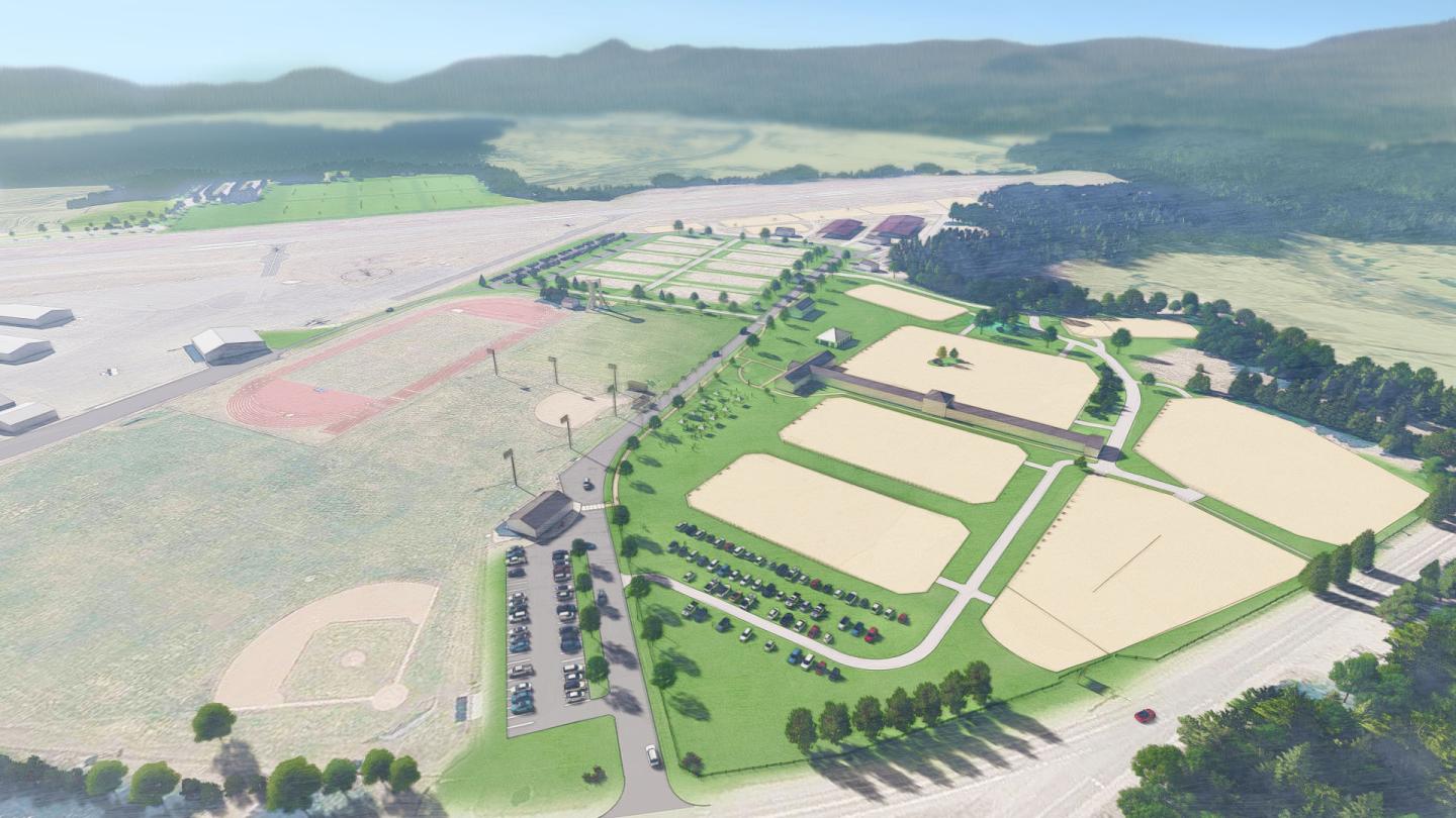 Sprawling sports complex with fields, trees, and parking, surrounded by countryside.