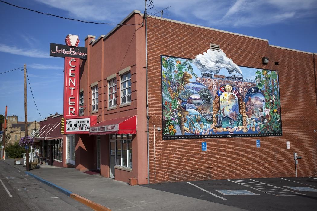 Brick building with a colorful mural, under a blue sky.