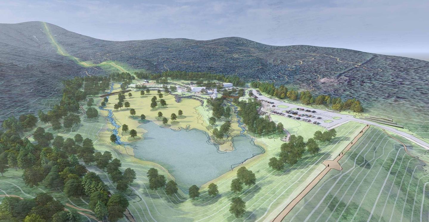 Aerial view of a green landscape with a large pond and surrounding hills.