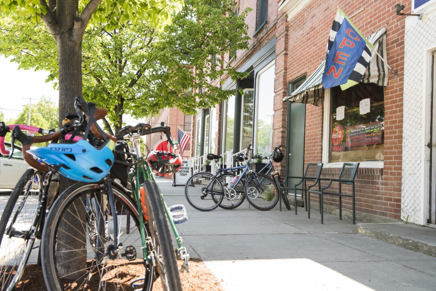 Bicycles parked outside a brick building with an open sign and outdoor seating.
