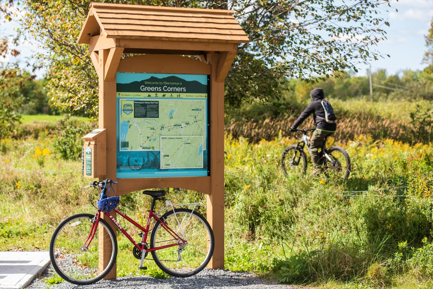 Trail map in a park, with two bicycles and a cyclist riding off-path.